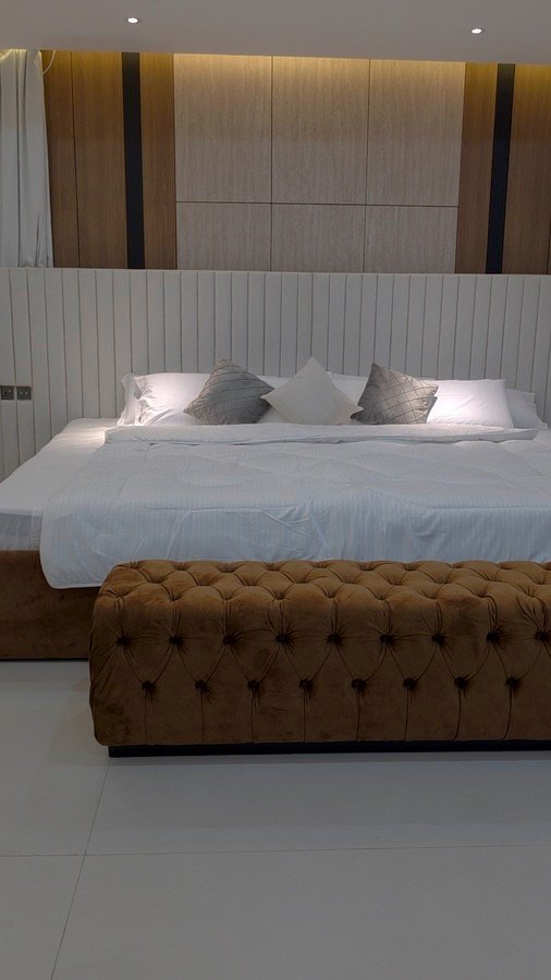 Completed bedroom with a wide upholstered headboard and timber feature wall